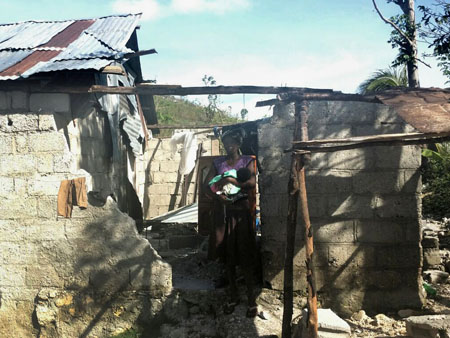 Maman et son bébé au milieu des ruines de leur maison, après le passage de l’ouragan Matthew