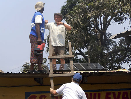 Les volontaires d’Energy Assistance installent les panneaux solaires sur le toit de l’école